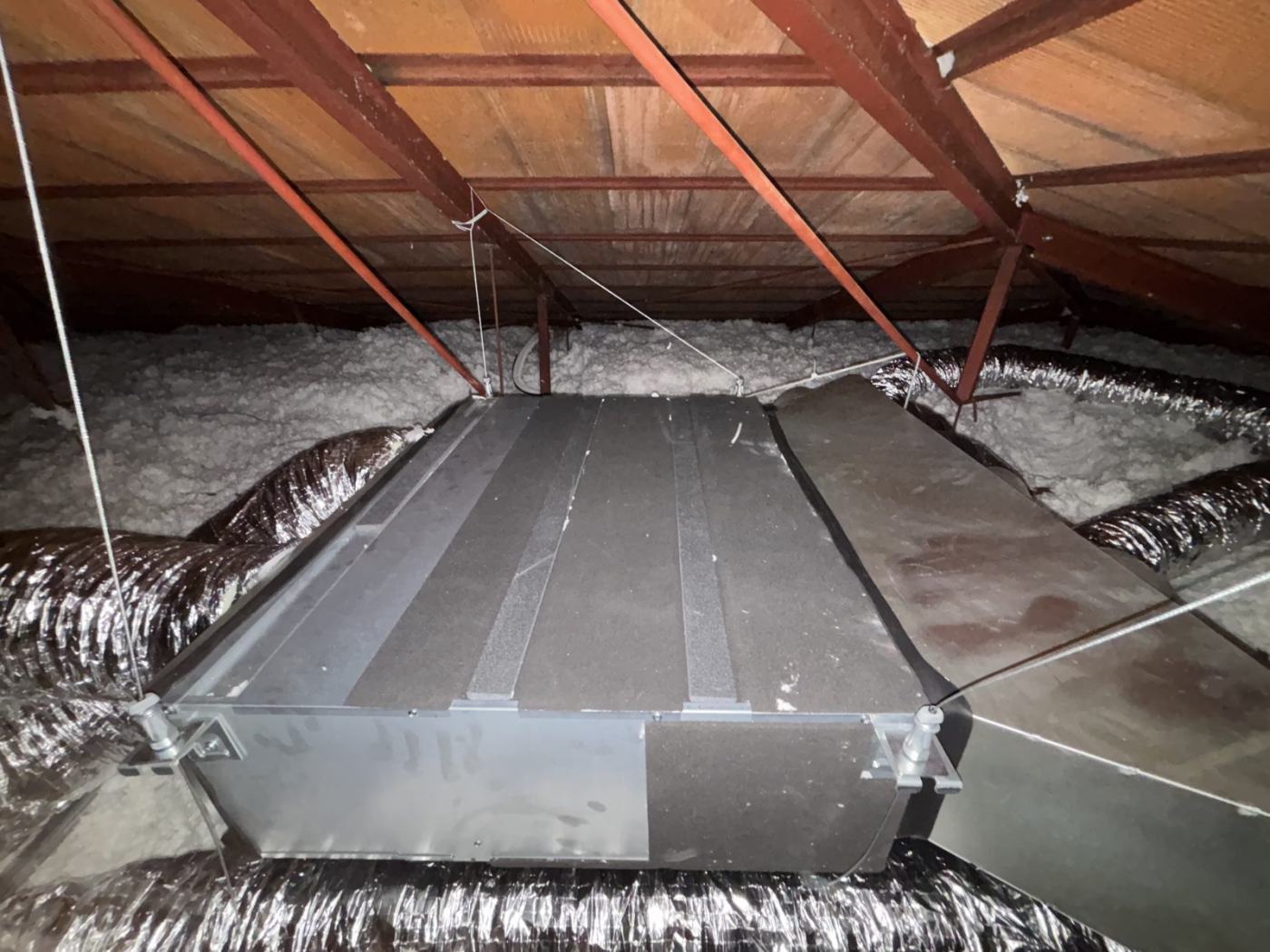 Unité de climatisation gainable et conduits isolés installés dans des combles